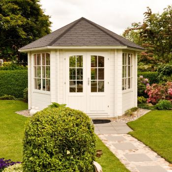 Valge aiamaja kuues aknaga ja topeltustega, paigutatud hästi hooldatud rohelise muru ja kivitee peale.