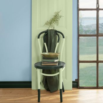 Pastellroheline tool, millele on asetatud must seljakott ja raamatud. Taustal suur aken ja helesinine sein.