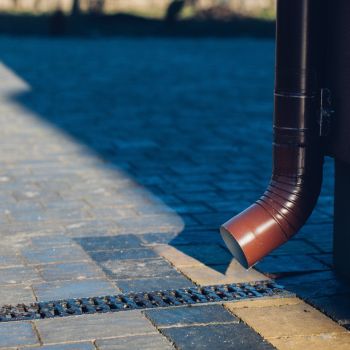 Punakaspruun vihmaveetoru suunab vett hallile sillutatud teele, tagades efektiivse vee äravoolu.