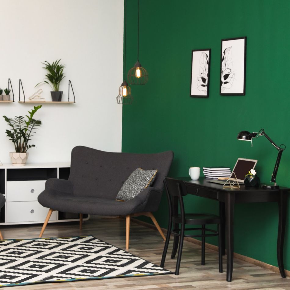Kaasaegne kodukontori sisekujundus, mis sisaldab halli diivanit, musta lauda, rohelist seina ja geomeetrilise mustriga vaipa.