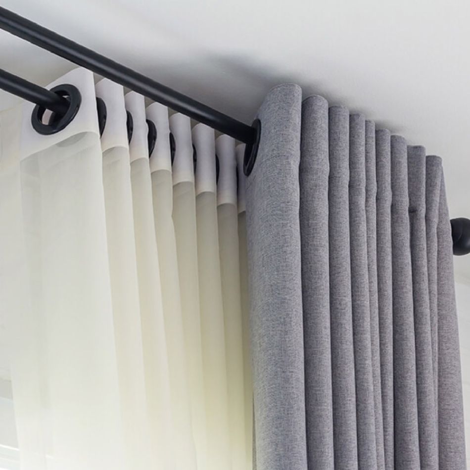 Hallid ja valged pimendavad kardinad rippuvad mustal kardinapuul, lisades ruumile kaasaegse ilme.