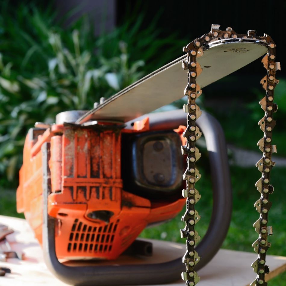 Oranži mootorsae pilt, millel nähtav terav keti ja musta värvi käivitusnupp.