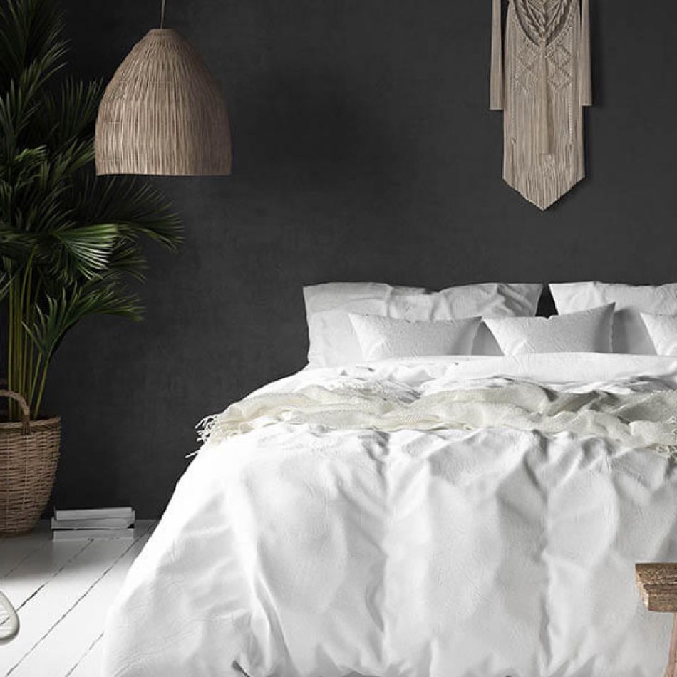 Kaasaegne magamistuba tumeda seinaga, valge voodipesu, rottangist valgustid ja seinal dekoratiivne puitpaneel.